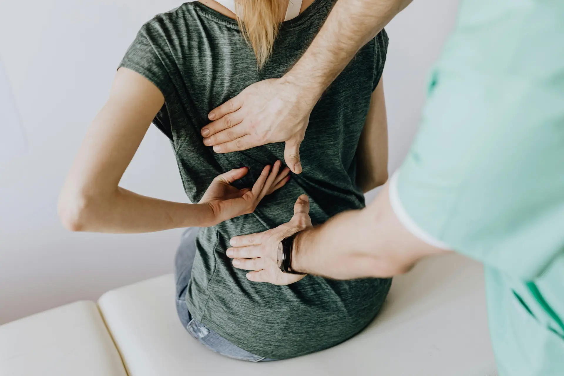Especialista en ortopedia examinando la zona lumbar de una paciente