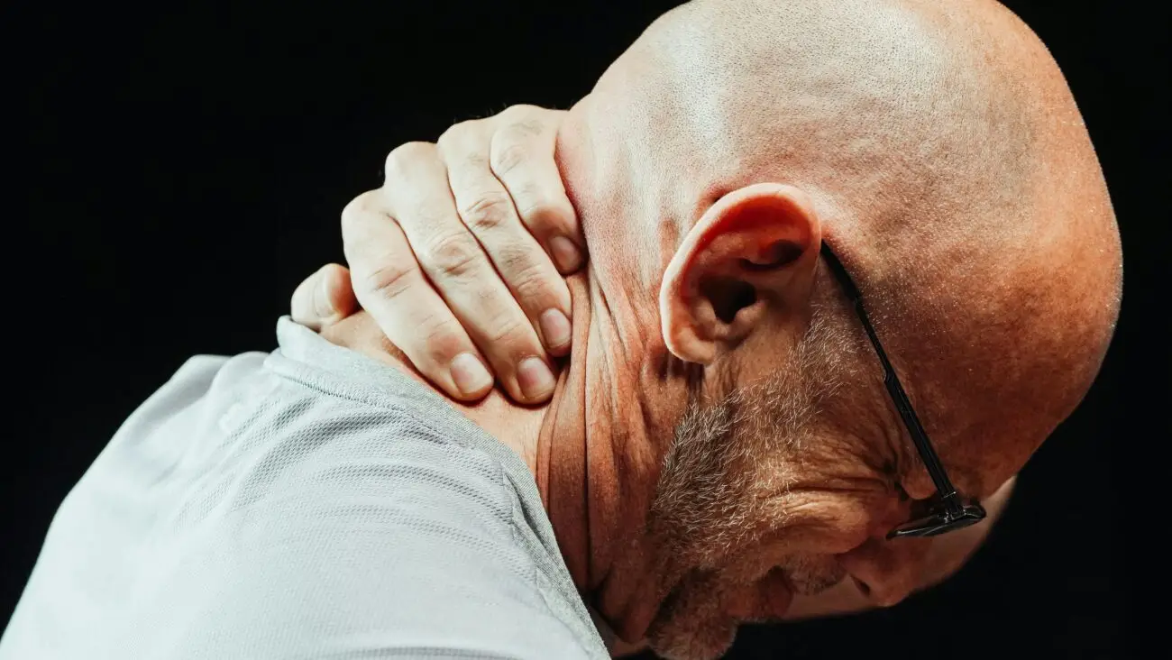 MAN HOLDING HIS NECK IN PAIN AFTER A CAR ACCIDENT WHIPLASH